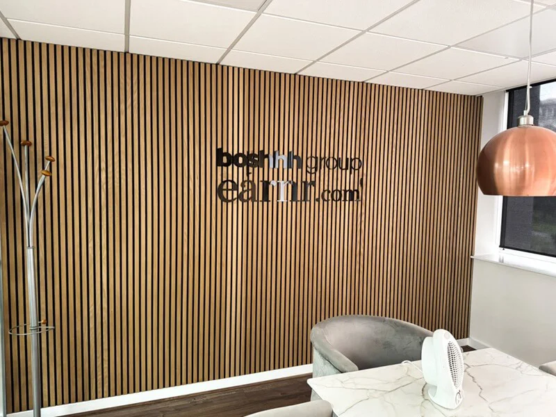 An image of the black Boshhh interior wall signage against vertical wood.